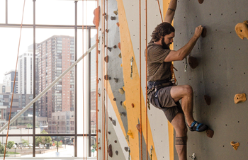 male student climbing rock wall