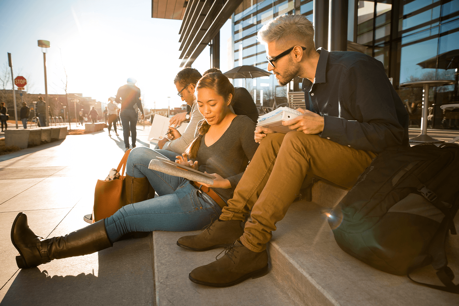 four students sitting on steps outside of Student Commons building studying