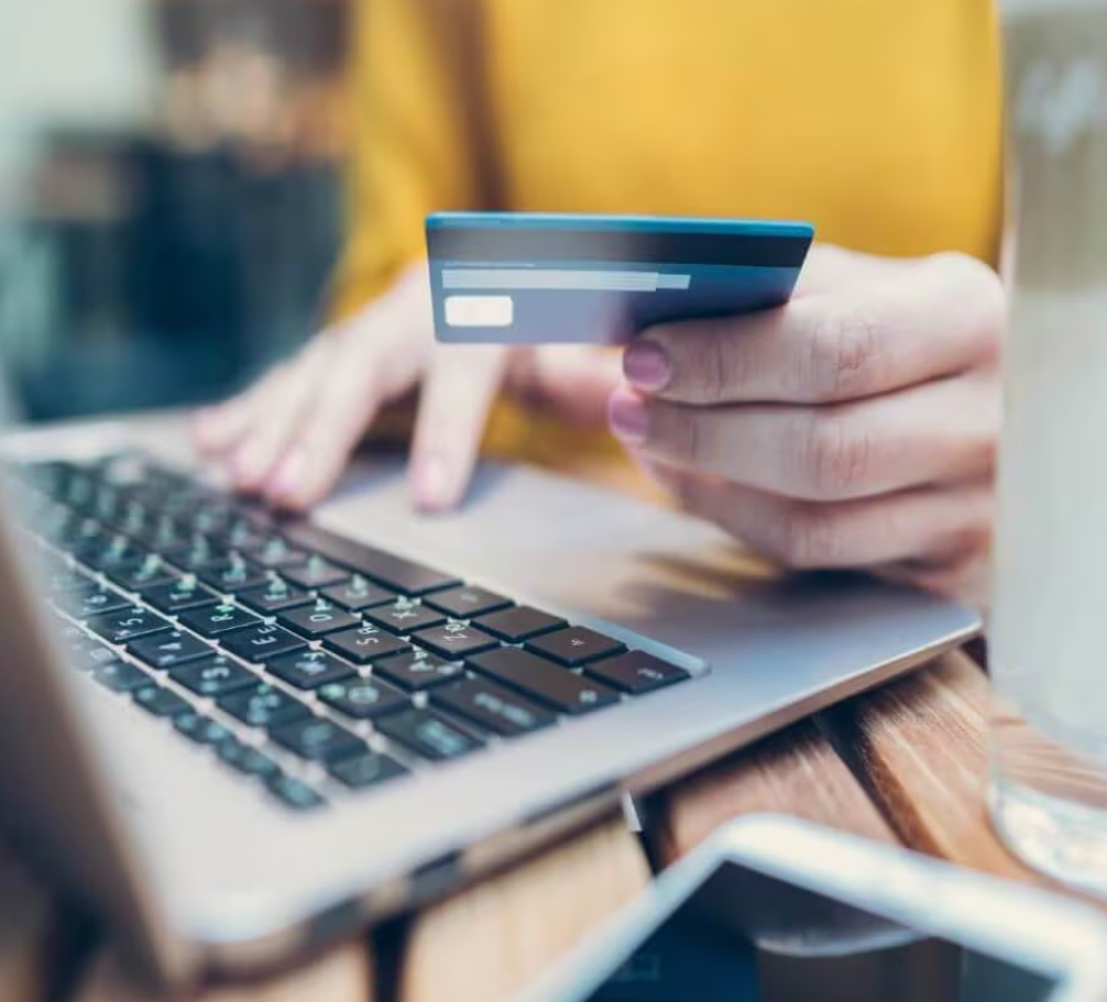 a person holding a credit card with a laptop next to it