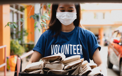 woman holding bag lunches wearing volunteer t-shirt