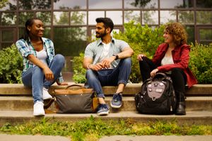 two females and one male sitting on steps outside