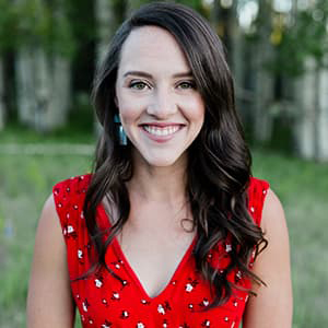 Image of Katie Imhoff with long brown wavy hair, smiling with her teeth, and wearing a sleeveless red dress.