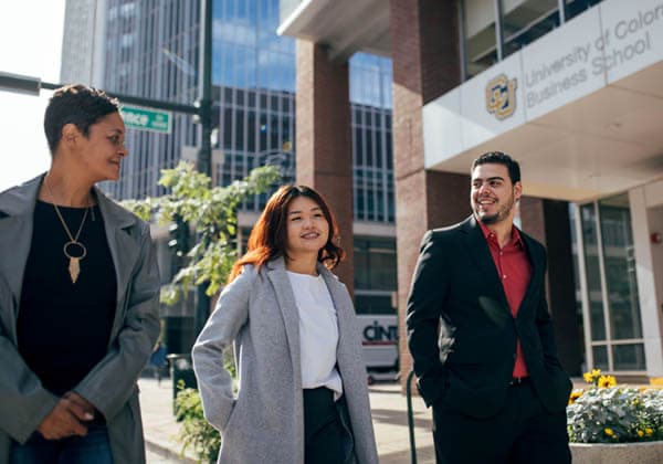 Three students walking in front of the Business School