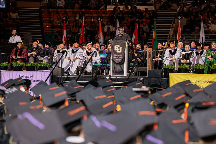 Commencement speaker Mayor Michael Hancock at the stanchion and a sea of grad caps in the foreground.