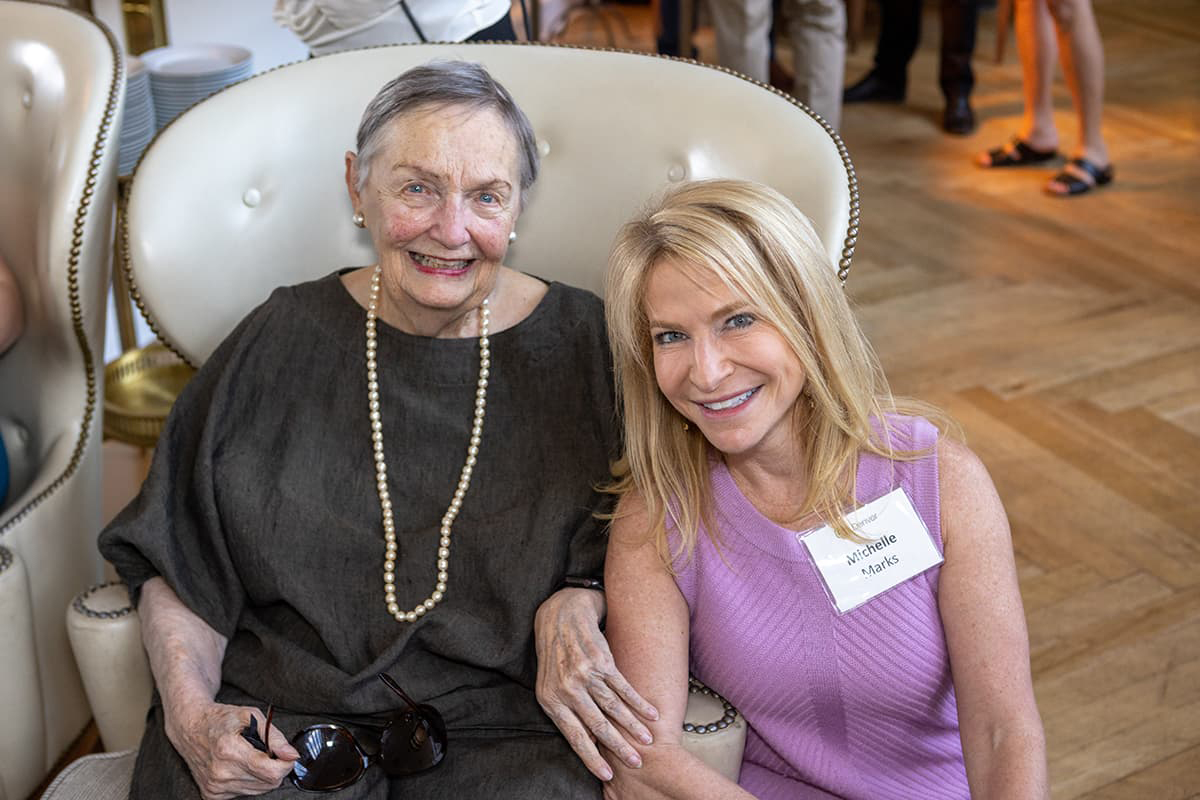 Photo of Dana Crawford and Chancellor Michelle Marks seated closely and smiling with their teeth.