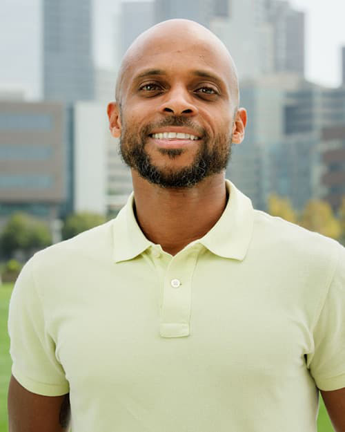 Antwan Jefferson wearing a yellow polo shirt, no head hair, a short dark beard, and smiling with his teeth. 