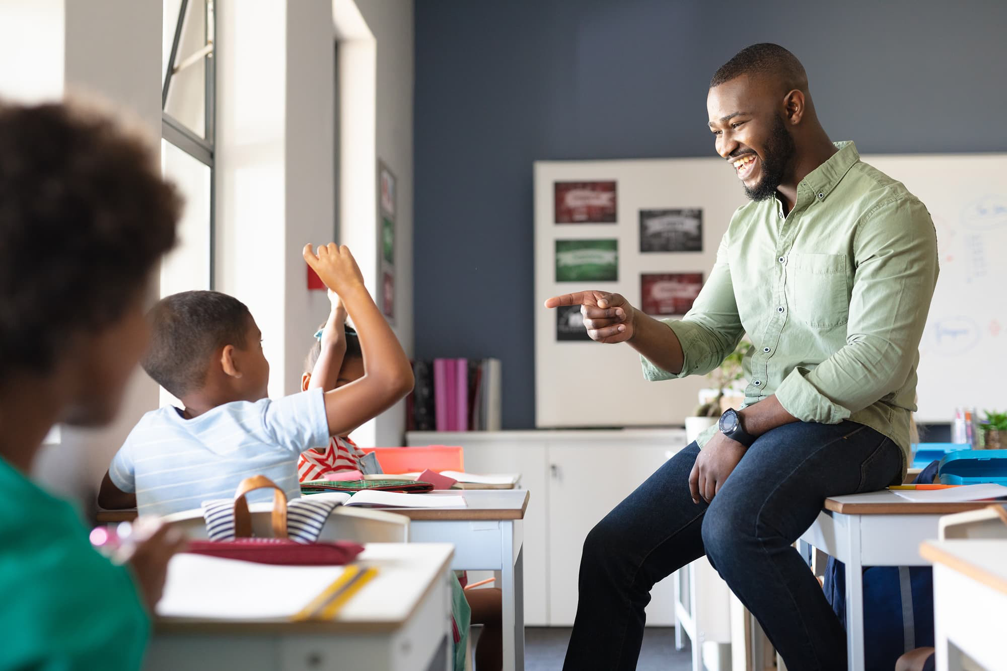 Teacher interacting with young students in a classroom.