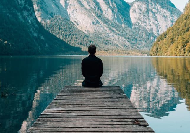 A person sitting by a placid lake