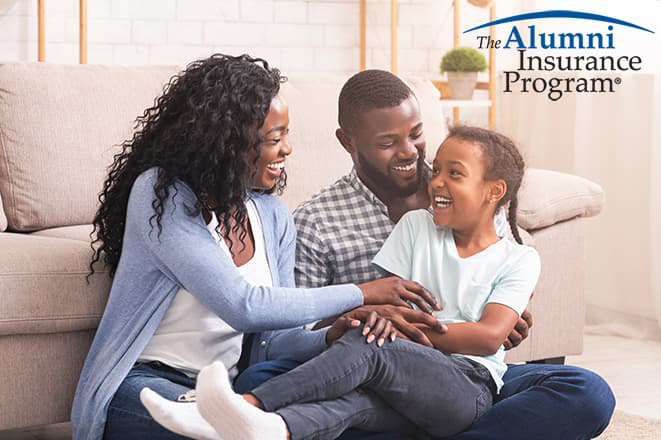 Mother and father playing with a child on the floor, smiling.