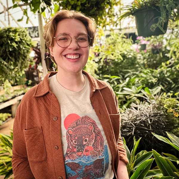 Headshot of Donalyn White with short blonde hair and an orange jacket smiling with their teeth.