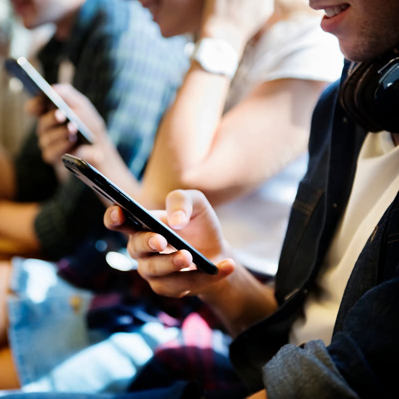 Group of people seated in a row looking at their smart phones.