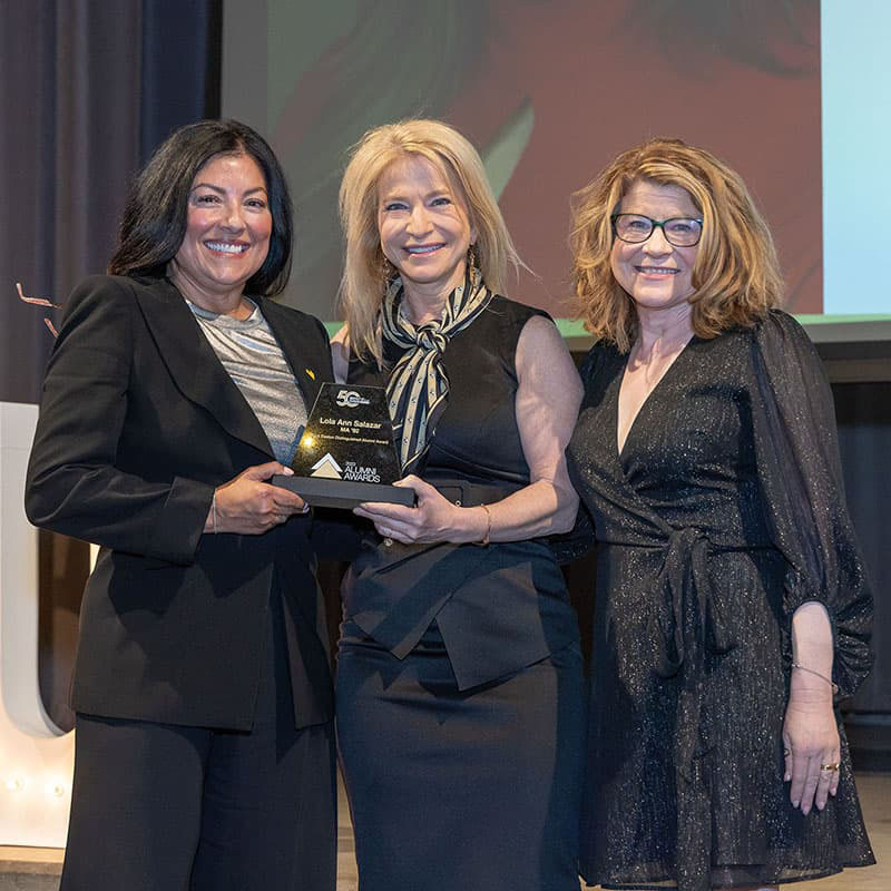 Lola Salazar receiving an alumni award from Chancellor Michelle Marks and Melisa Baldwin.