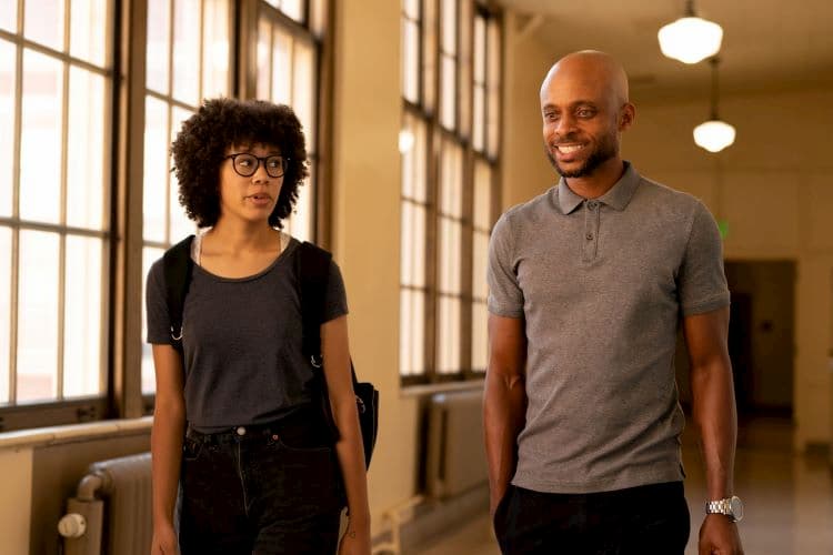 A man and woman walking down a hall and talking