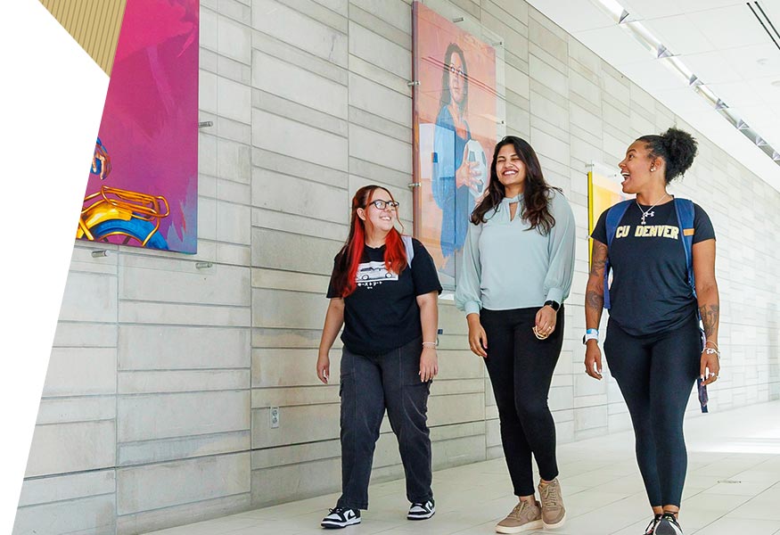 Three students walking in hallway discussing class