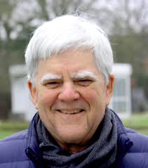 Close-up headshot of Clayton Lewis smiling in scarf outdoors