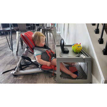 Young child sits contently in front of switch adapted fan toy.