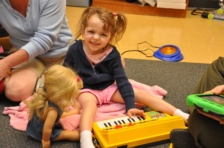 A young girl plays with adapted toys and smiles