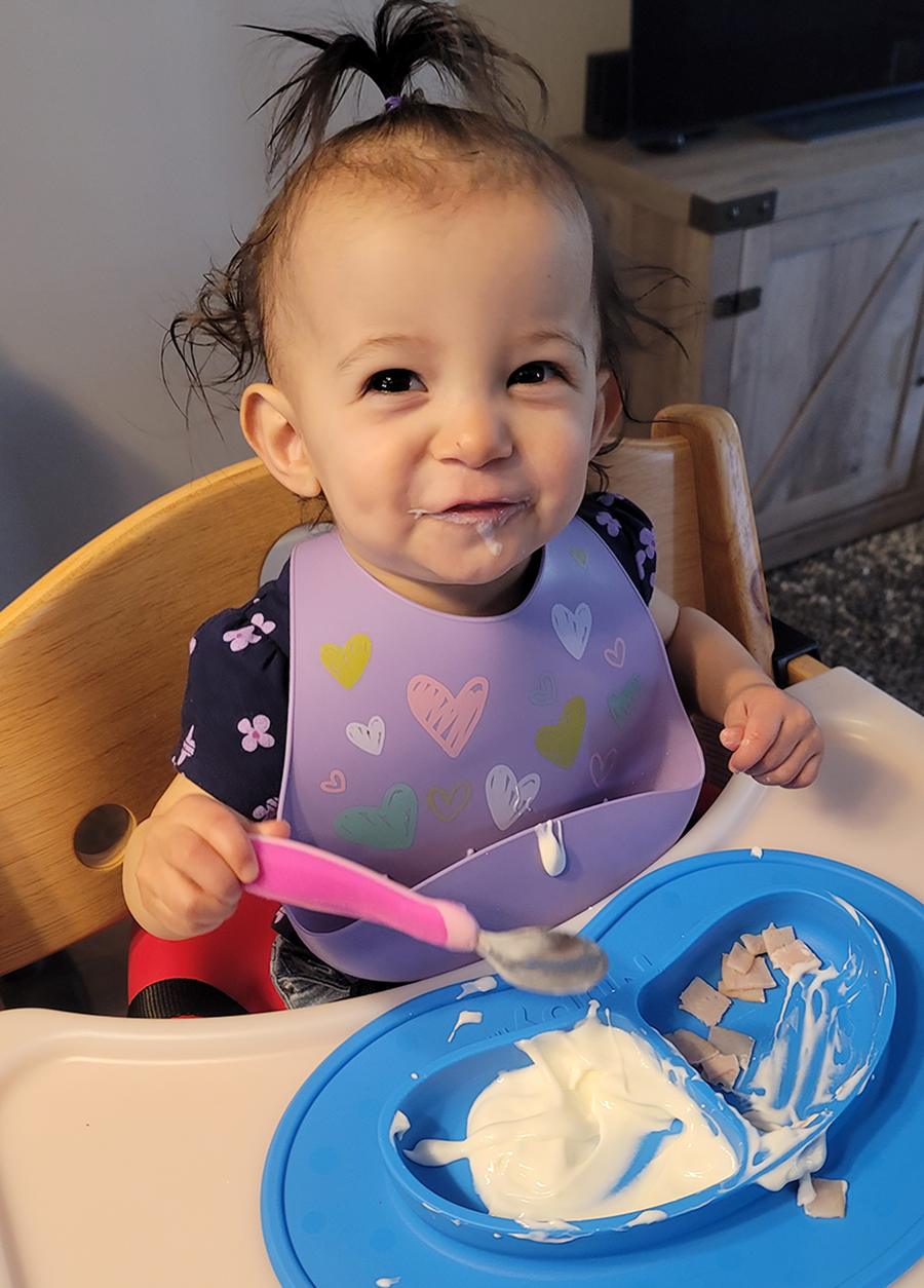 A young girl sits in an adaptive high chair