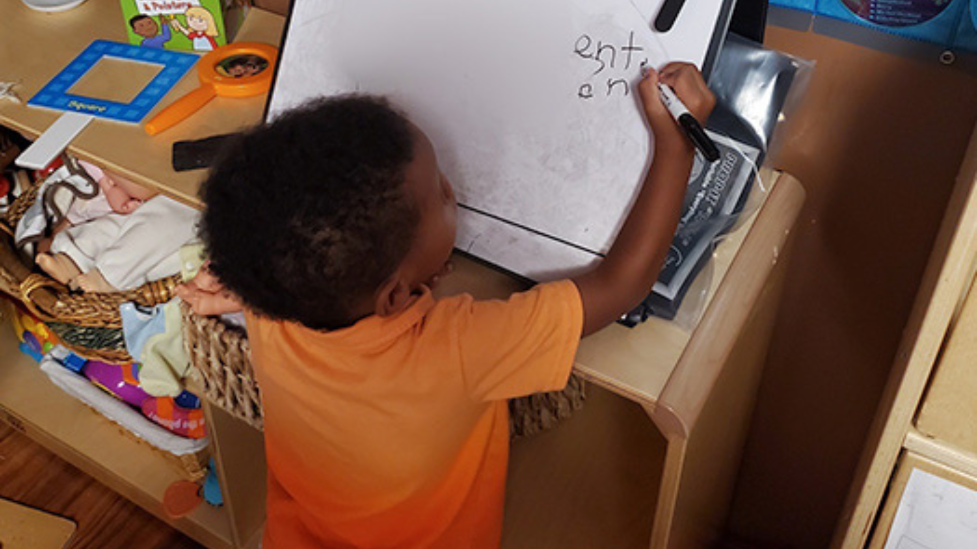 A boy draws on a whiteboard easel