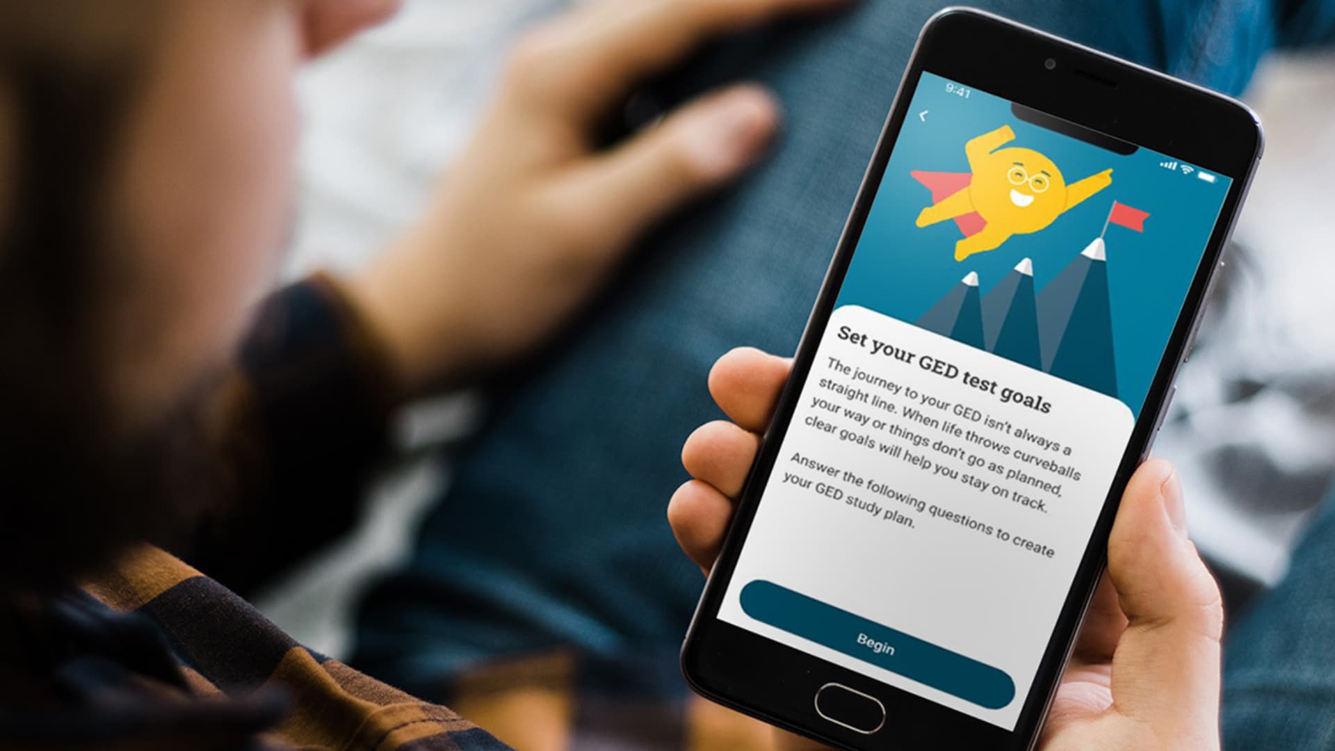 A man holds a smartphone with the GED and Me app open on the screen